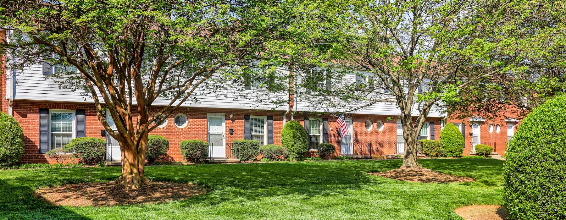 connected homes with a lawn and trees in front of it